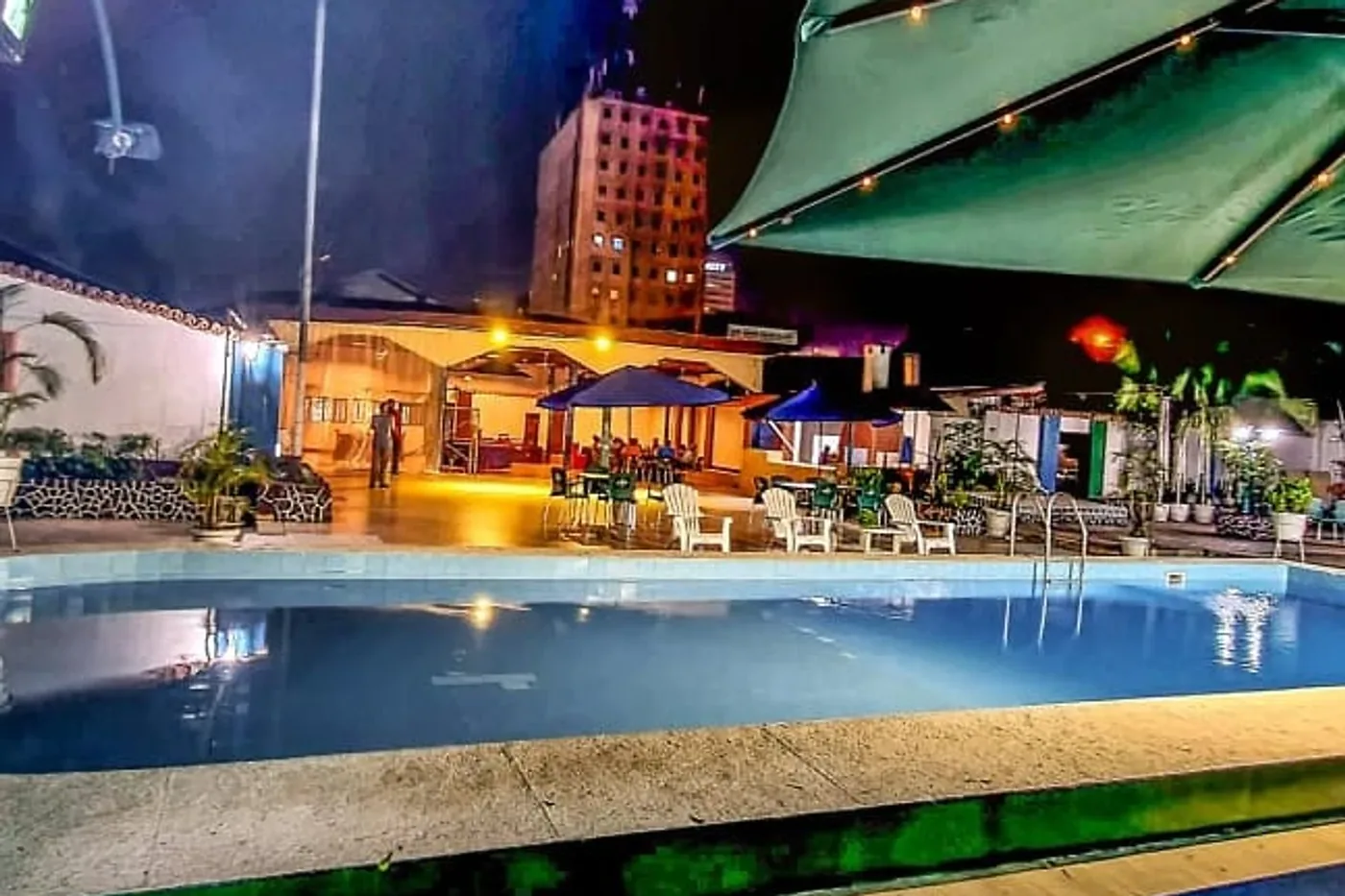 Piscine de l'hôtel Léon illuminée de nuit, avec transats