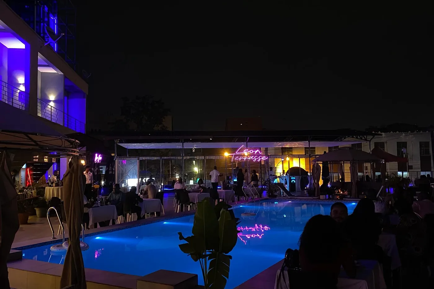Piscine éclairée la nuit, terrasse restaurant animée